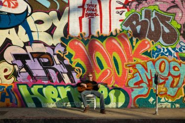 Young Musician on Street with Graffiti